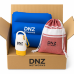 Eine geöffnete Versandbox mit Sommer-Werbeartikeln von „DNZ NETWORKS“, bestehend aus einem blauen aufblasbaren Kissen, einer weiß-gelben Sonnencreme-Tube mit Karabiner und einem rot-weiß gestreiften Stoffbeutel.