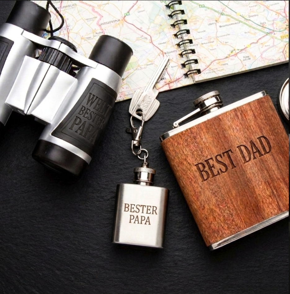 Outdoor-Geschenkset für Väter mit silbernem Fernglas, graviertem Holz-Flachmann, Kompass-Schlüsselanhänger und Landkarte auf Schiefer.
